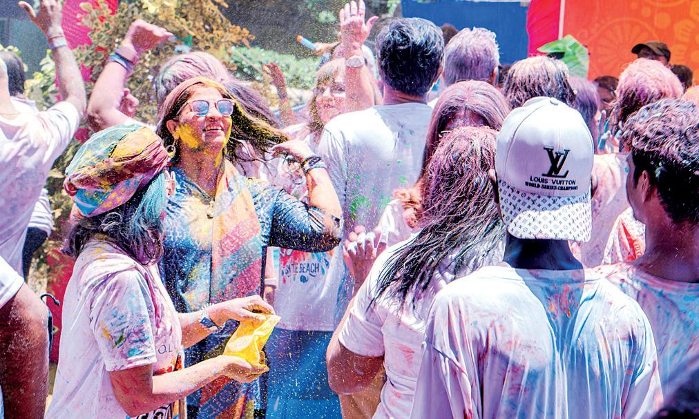 BAREFOOT IN THE SAND DRENCHED IN COLOR HOLI BY THE BEACH AT ITS PUREST