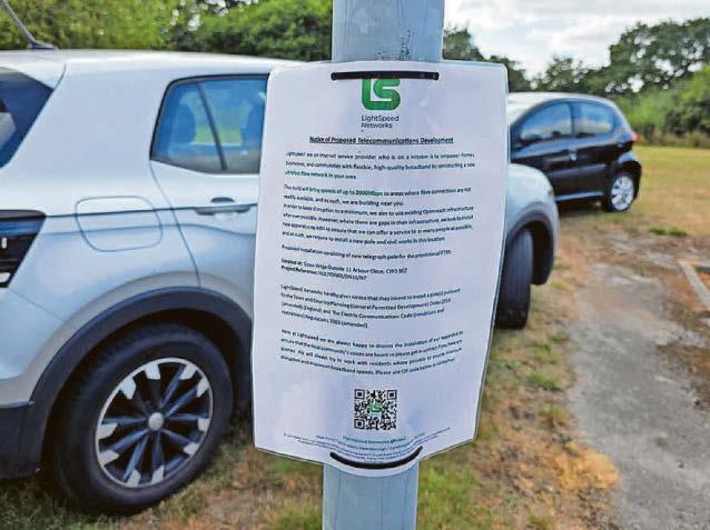 Cars parked off road to block telegraph poles being put up