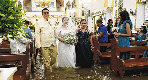 Wading down the aisle: Filipino couple tie the knot in flooded church
